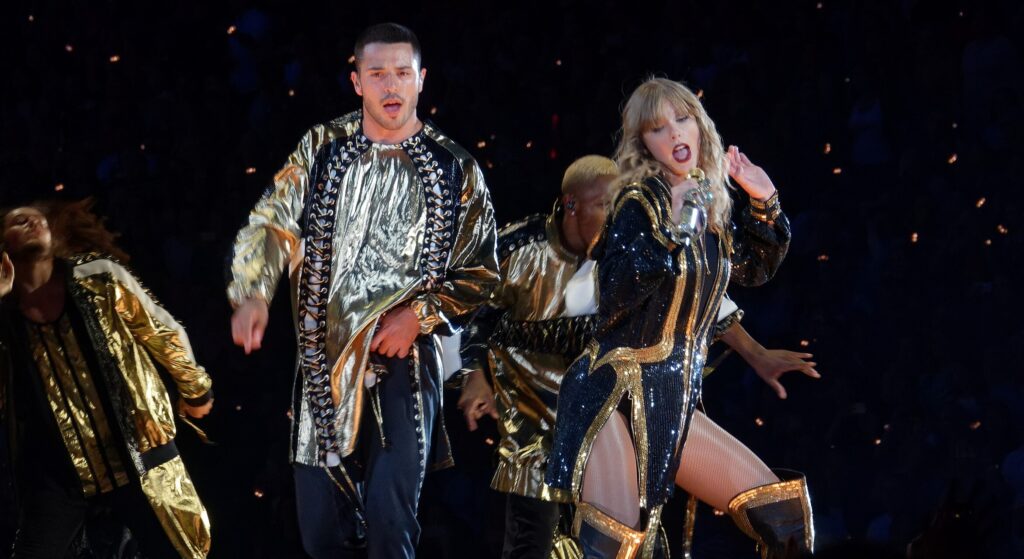 Taylor Swift performing on stage in a glittering outfit under stage lights, representing her record-breaking streaming success